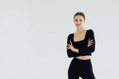 Katlanmış silah ile duran spor kadın gülümseyerek ve beyaz bir arka plan üzerinde izole kamera bakıyor