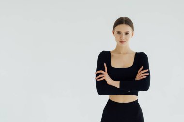 Katlanmış silah ile duran spor kadın gülümseyerek ve beyaz bir arka plan üzerinde izole kamera bakıyor