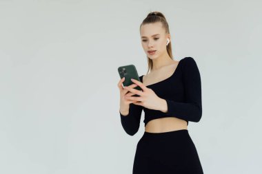 Portrait of a woman listening to music with headphones and mobile phone isolated over white background