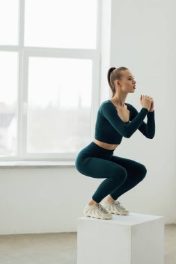 Genç bir kadın egzersiz rutininin bir parçası olarak bir kutuya atlıyor. Spor salonundaki spor salonunda spor yapan jimnastikçi kadın..