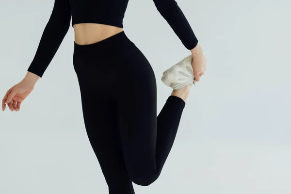 年轻的健身女子站和伸展双腿 在白色背景侧面视图肖像 — 图库照片