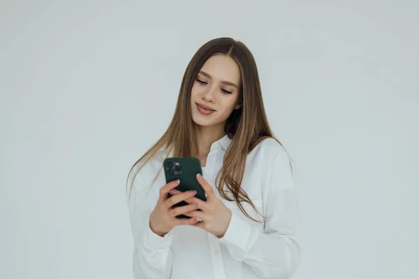 Молода Брюнетка Посміхається Під Час Використання Мобільного Телефону Ізольовано Білому — стокове фото