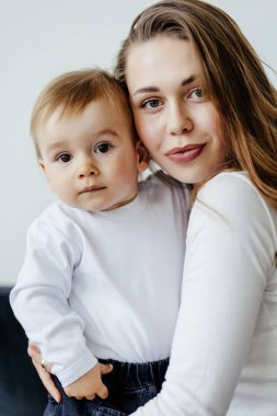 Mutlu genç bir kadın, küçük oğluyla sarılıp yatıyor. Stüdyoda kanepede birlikte eğleniyor..