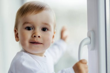 Küçük, düşüncelere dalmış ve iki yaşında üzgün bir çocuk pencerenin kenarında oturmuş bir şeyler düşünüyor ve bekliyor..