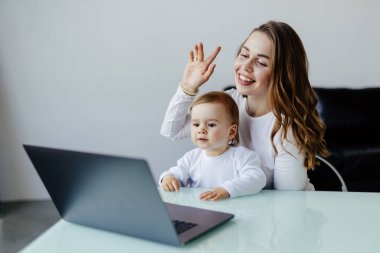 Tıp, teknoloji ve sağlık kavramı - dizüstü bilgisayar evde aile doktoru ile görüntülü sohbet sahip bebek oğluyla mutlu anne