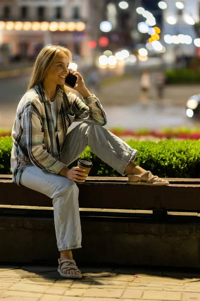 Молодая Женщина Разговаривает Телефону Сидя Скамейке Ночное Время Городской Улице Стоковое Фото