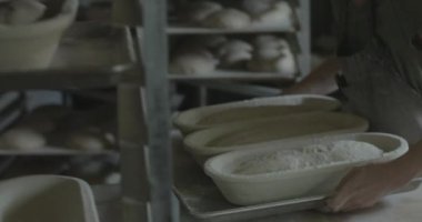 Fırıncı bir fırının rafına ekmek hamuru koyar..