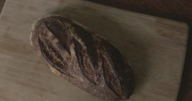 Adam kesme tahtasından taze bir ekmek alıyor..