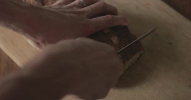 Adam kesme tahtasına taze bir somun zanaatkar ekmeği kesiyor..