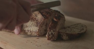 Adam kesme tahtasına taze bir somun zanaatkar ekmeği kesiyor..