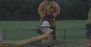 İtfaiyeci acil müdahale eğitimi sırasında yangın hortumunu açmak için yangın musluğu açar..