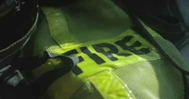 Sarı itfaiye yeleği kullanıma hazır bir itfaiye aracının içinde duruyor..