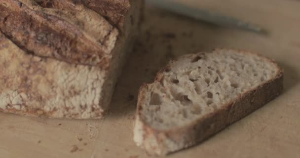 Egy friss vekni kézműves kenyér ül egy vágódeszkán..