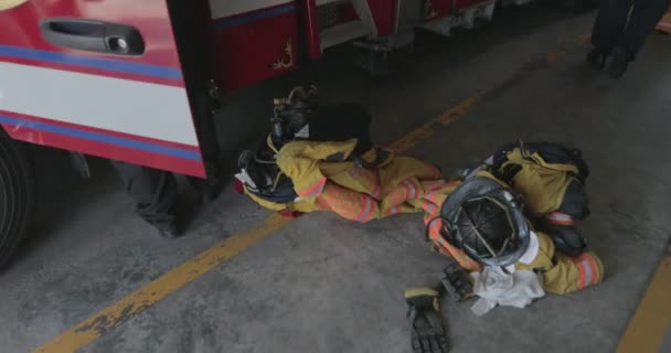 消防車は消防署内の床に座り 消防士が装備を準備して緊急事態に対応する準備ができています — ストック動画