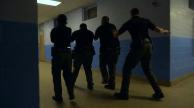 Bir grup polis okul çatışmalarına müdahale etmek için silahlarını kuşanmış bir şekilde okula giriyor..