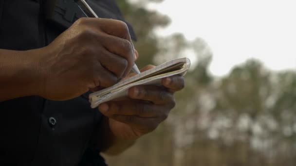 Egy Afro Amerikai Rendőr Feljegyzést Egy Füzetbe — Stock videók