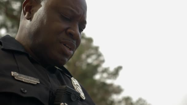 Офицер Афроамериканской Полиции Разговаривает Кем Смотрит Вниз Блокнот — стоковое видео