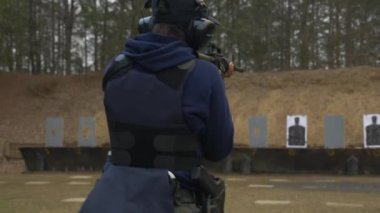 Polis memuru atış talimi sırasında tüfeğiyle atış poligonunda yürüyor..