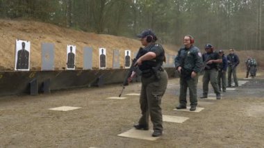 Bir grup polis, atış talimi için atış poligonunda silahlarını ateşliyor..