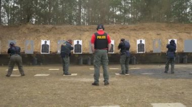 Bir grup polis, atış talimi için atış poligonunda silahlarını ateşliyor..