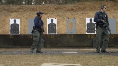 Bir grup polis, atış talimi için atış poligonunda silahlarını ateşliyor..