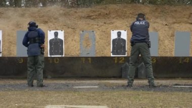 Bir grup polis, atış talimi için atış poligonunda silahlarını ateşliyor..
