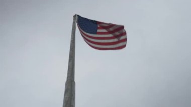 Fırtınalı bir günde bayrak direğinde dalgalanan bir Amerikan bayrağı.