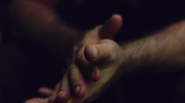 Dışarıdaki fırtınadan yıldırım çakarken bir erkek yürüyüşçünün bir mağarada ellerini ovalarken çekilmiş bir fotoğrafı..