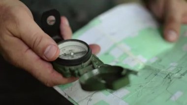 Manyetik lensatik pusula ve patikada yürüyüş için topoğrafik harita kullanan bir adamın el kamerası görüntüsü..