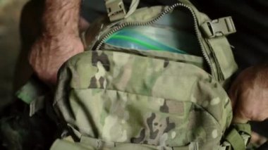 Kamuflaj çantasının fermuarını çeken bir adamın el kamerası görüntüsü..