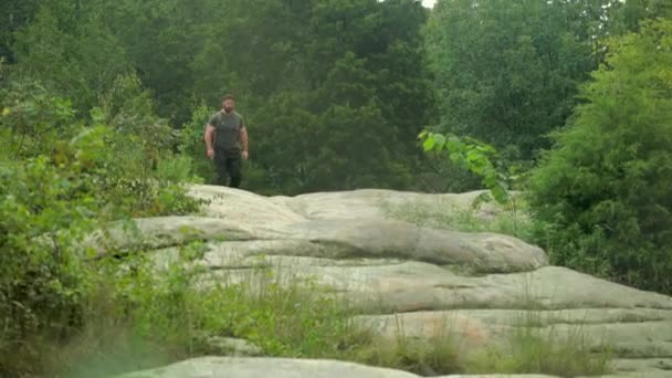 大きな岩の上に男ハイカーバックパッキングのハンドヘルドショット — ストック動画