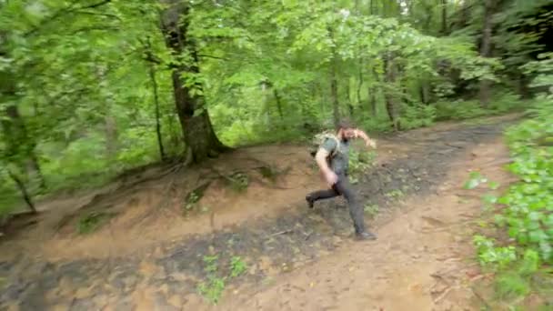 男のハイカーは泥の上をジャンプし 森の中の歩道に沿ってハイキング — ストック動画