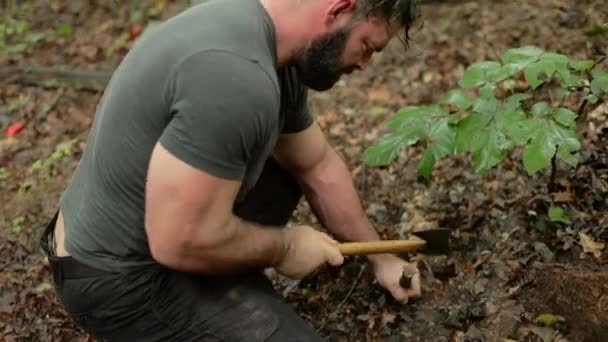 一名男子用斧头将幸存者掩蔽所的木桩锤入地下的手持射击 — 图库视频影像