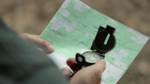 Przez Ramię Człowieka Używa Się Magnetycznego Kompasu Nawigacyjnego Mapy Płytkie — Wideo stockowe