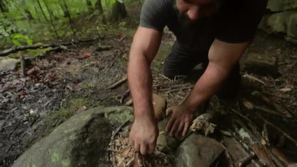 火の輪の中に小枝を使って小さなキャンプファイヤーを作る男の手持ち撮影 — ストック動画
