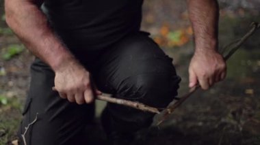 Erkek bir kampçı, odununu dizinde ağır çekimde kırar..