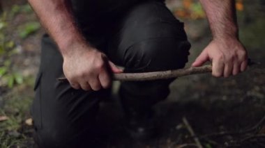 Erkek bir kampçı, odununu dizinde ağır çekimde kırar..