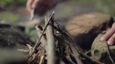 Ağır çekimde kamp ateşi için çubuk düzenleyen bir erkek kampçının ayrıntıları..