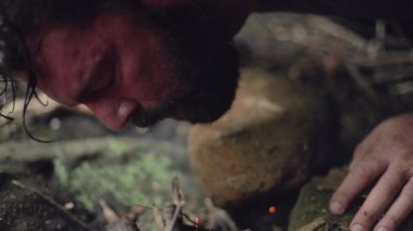 Erkek bir kampçı, yavaş çekimde başlamak için küçük bir kamp ateşine üfledi..