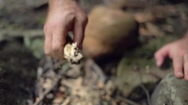 Erkek bir kampçı yavaş çekimde tutuşturmak için bir çubuktan parçalar koparır..