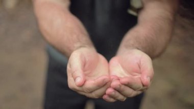 Erkek bir yürüyüşçü ellerini yağmurda yıkar. Yavaş çekimde damlar..