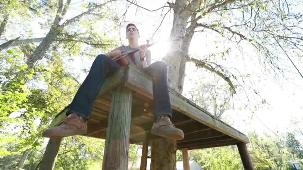 Nastolatek Gra Gitarze Platformie Drzew Podświetlone Jasnym Popołudniowym Słońcem — Wideo stockowe
