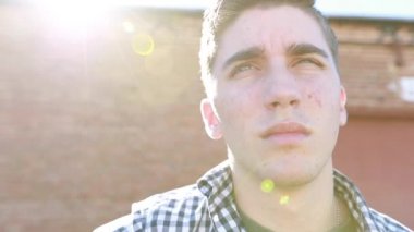 Genç çocuk arka planda eski bir tuğla bina ile yavaş çekimde gitar çalar..