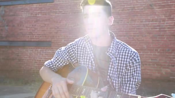 Adolescente Chico Toca Guitarra Con Viejo Edificio Ladrillo Fondo — Vídeo de stock