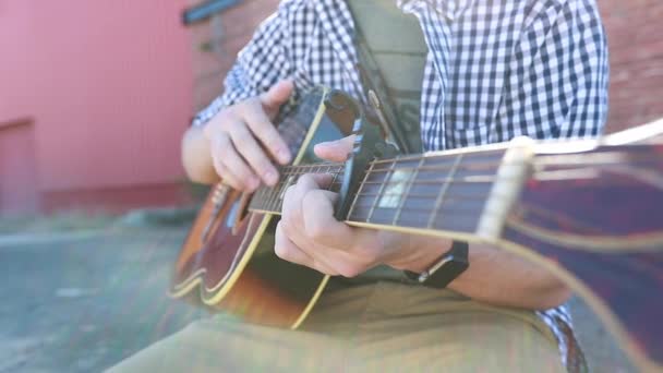 十几岁的男孩以慢动作的细节弹吉他 背景是一座古老的砖楼 — 图库视频影像