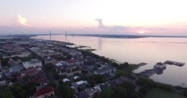 Güneş doğarken Charleston, SC çatıları ve limanı Ravanel köprüsü ve rıhtım manzaralı..