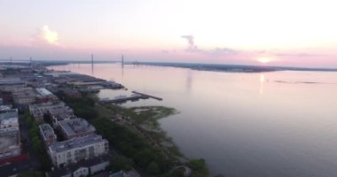Güneş doğarken Charleston, SC çatıları ve limanı Ravanel köprüsü ve rıhtım manzaralı..