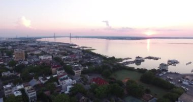 Güneş doğarken Charleston, SC çatıları ve limanı Ravanel köprüsü ve rıhtım manzaralı..