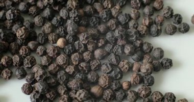 Beyaz tabakta karabiber, sağlıklı yemek pişirmek için baharat olarak kullanılmaya hazır..