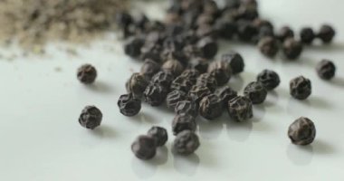 Siyah biber ve beyaz tabakta bütün biber, sağlıklı yemek pişirmede kullanmak için bir yığın içinde..
